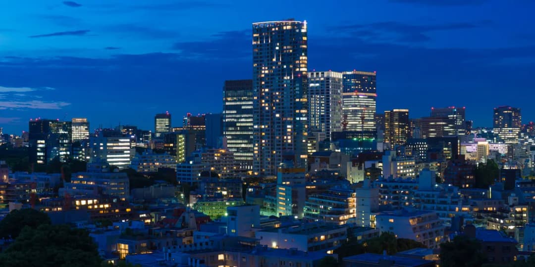 Tokyo office towers at dusk, windows lit across the Akasaka skyline